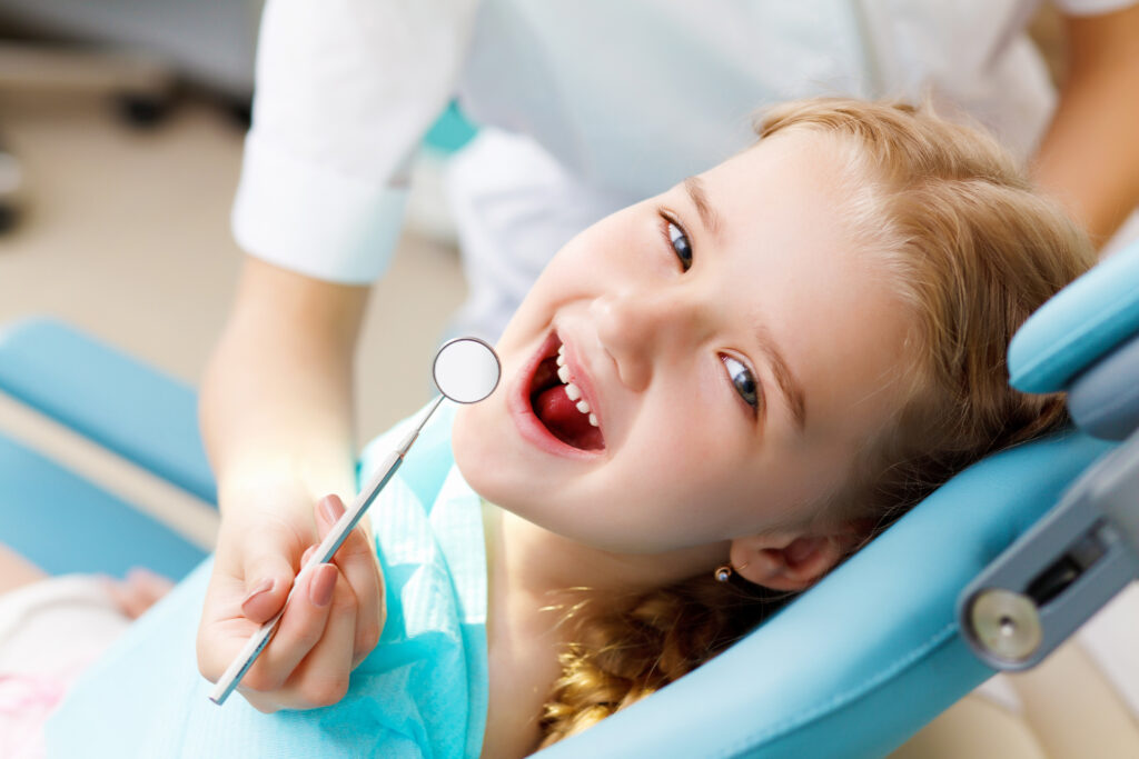 A girl in a dental chair opening her mouth